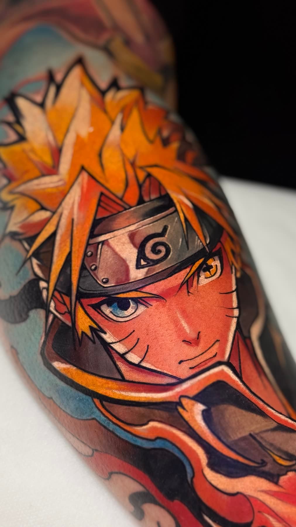 Braço fechado em cor: personagem de anime de cabelo loiro e faixa na testa, em laranja e azul