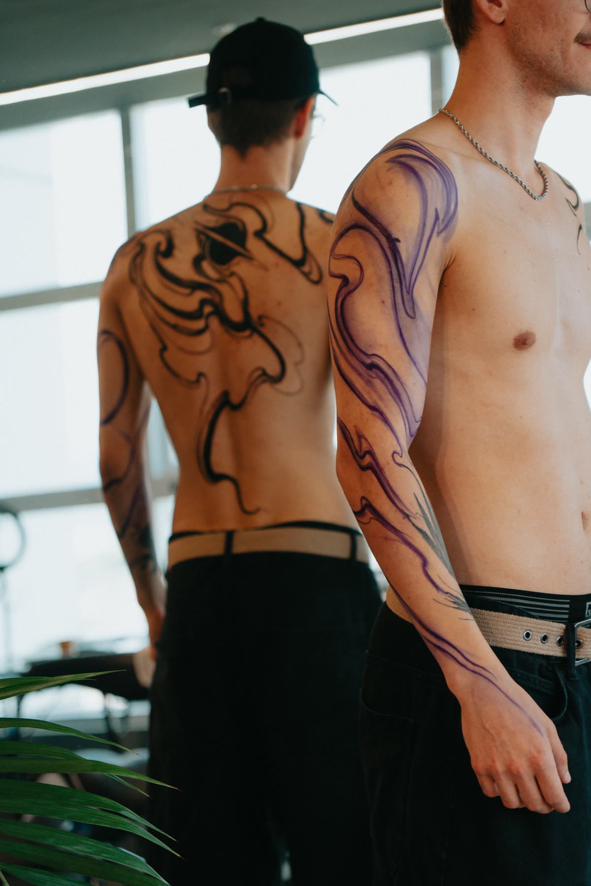 Cliente de pé junto à janela: as costas já tatuadas e o braço ainda em desenho