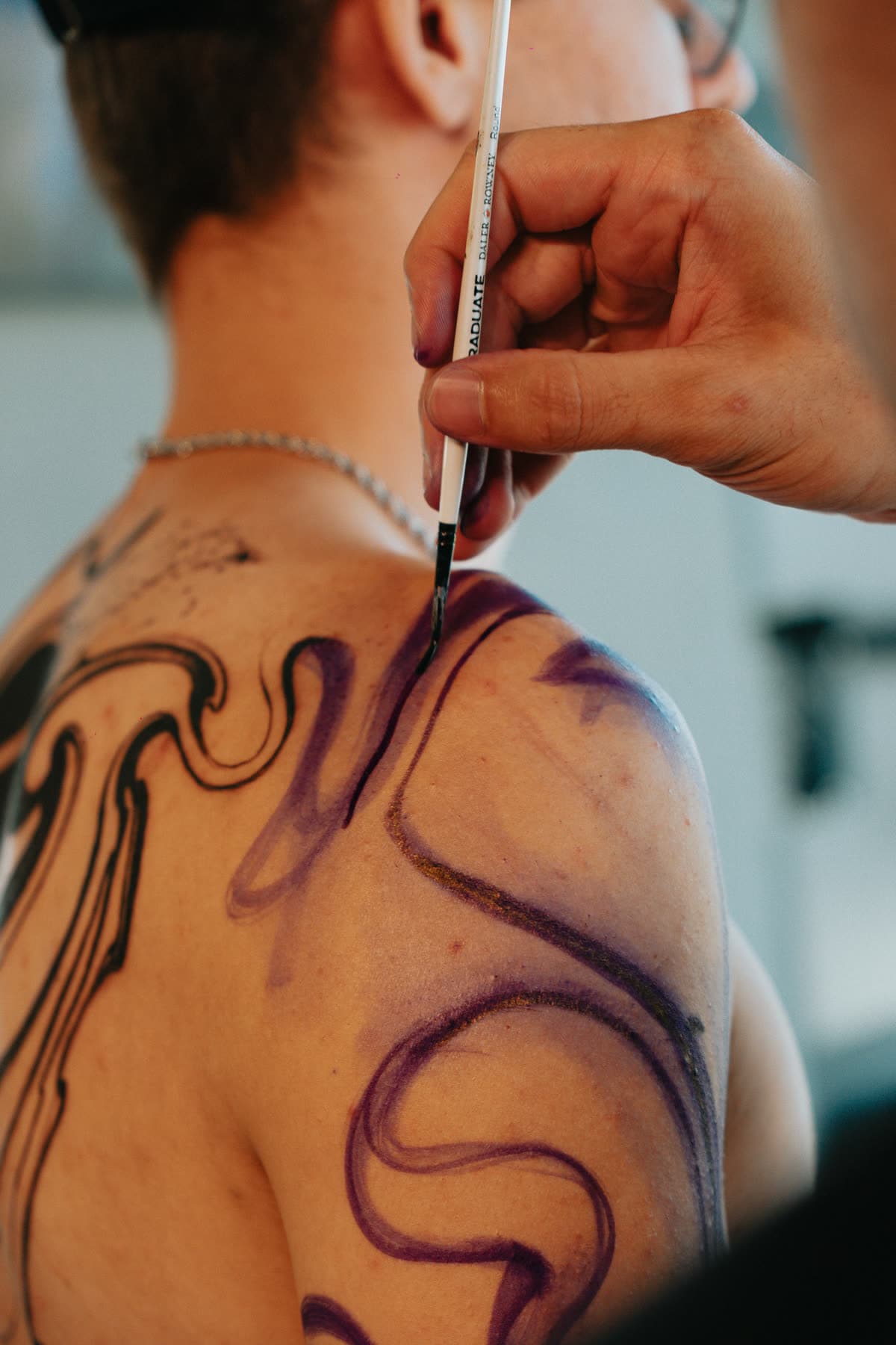 Close: caneta traçando o desenho sobre a omoplata do cliente