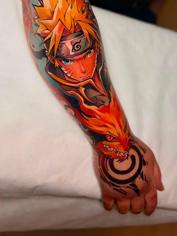 A tattoo finalizada: Naruto e a raposa em cor fechando o antebraço, com o selo na mão