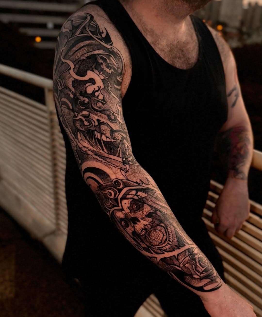 Braço fechado em blackwork: caveira, ornamentos e preto cheio, junto à janela do estúdio