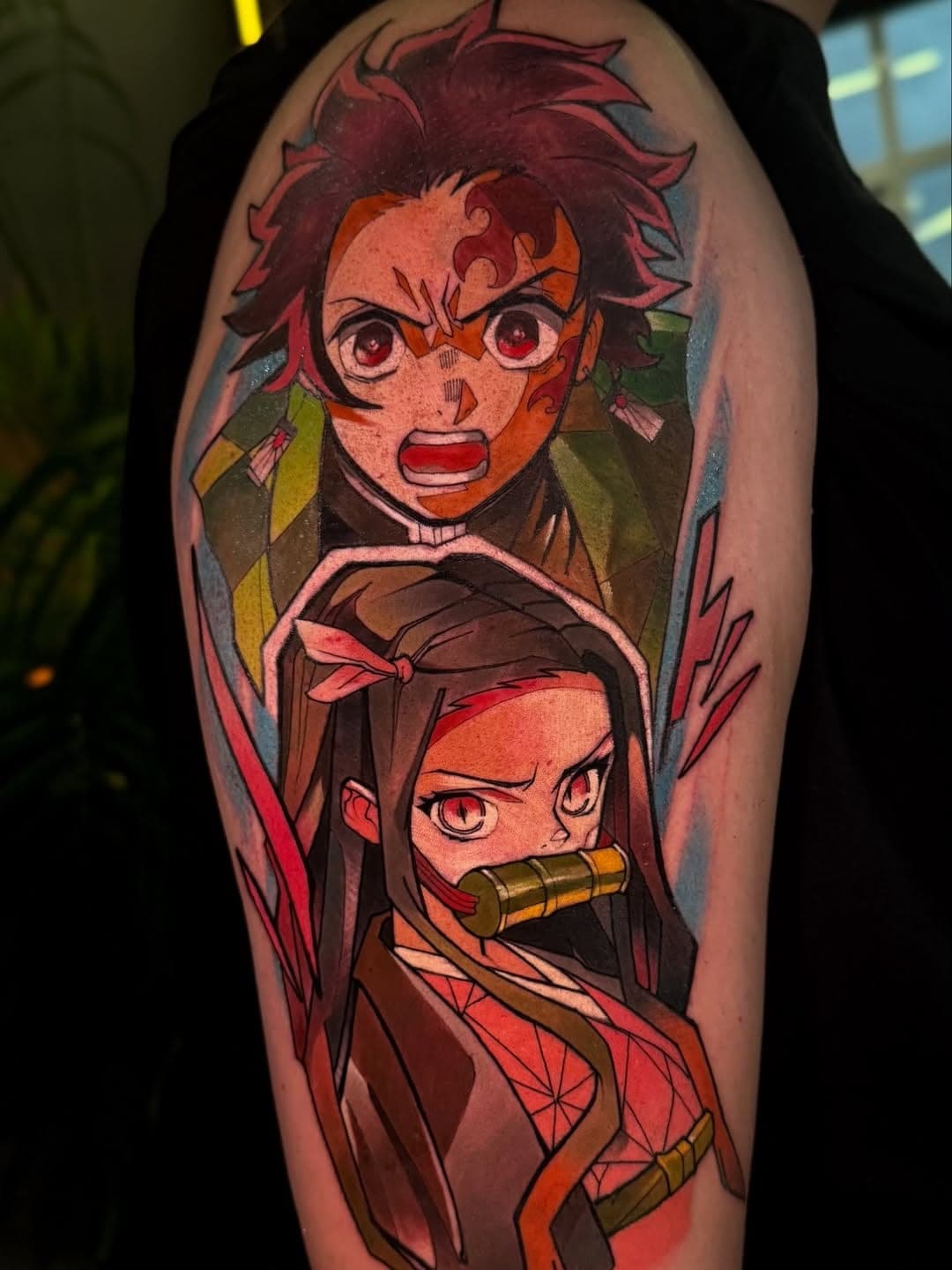 Braço em cor: dois personagens de anime, um de brincos e uma garota de bambu na boca