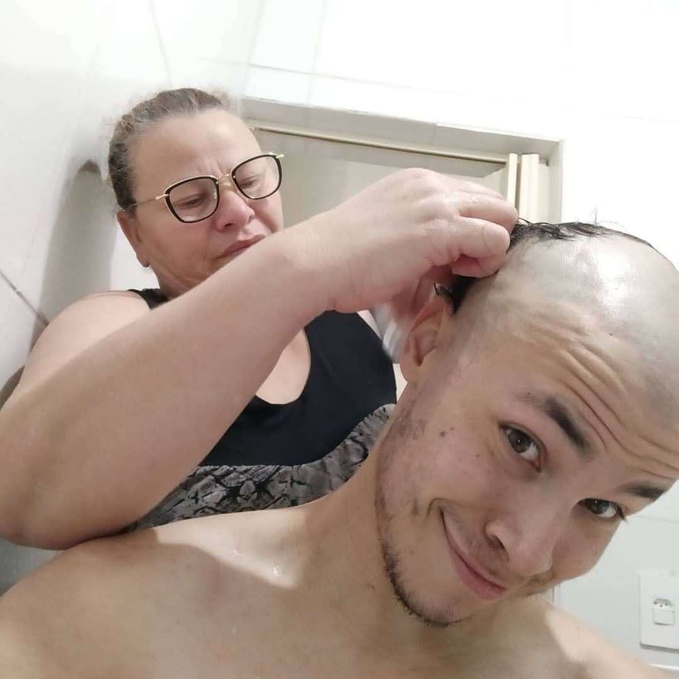 A mãe do Cláudio cortando o cabelo dele, ele sorrindo pra câmera