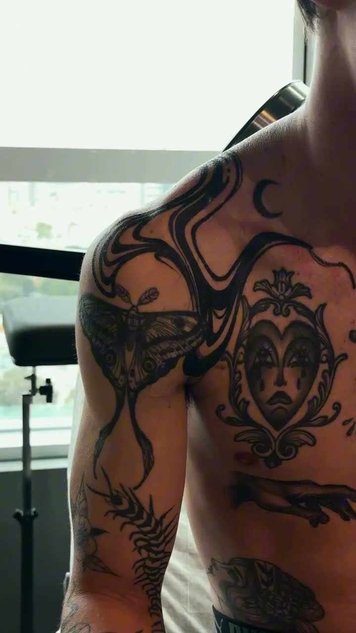 Vídeo: as formas pretas do suminagashi correndo pelo ombro e pelo peito, por cima de tatuagens antigas